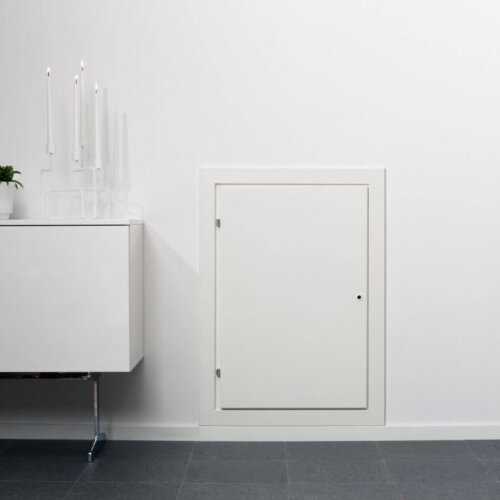 Pööningu- ja seinaluugid - elutuba, kus on seinas väike valge luuk, kõrval valge kapp koos küünalde ja taimega