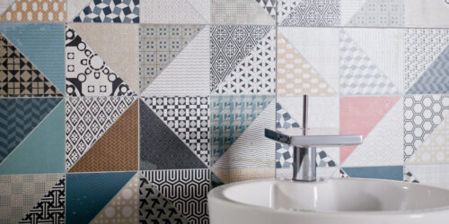 Plaadid - vannituba kroomitud segisti ja valge kraaniakusiga, seinas äge mustriline plaat erinevates värvides