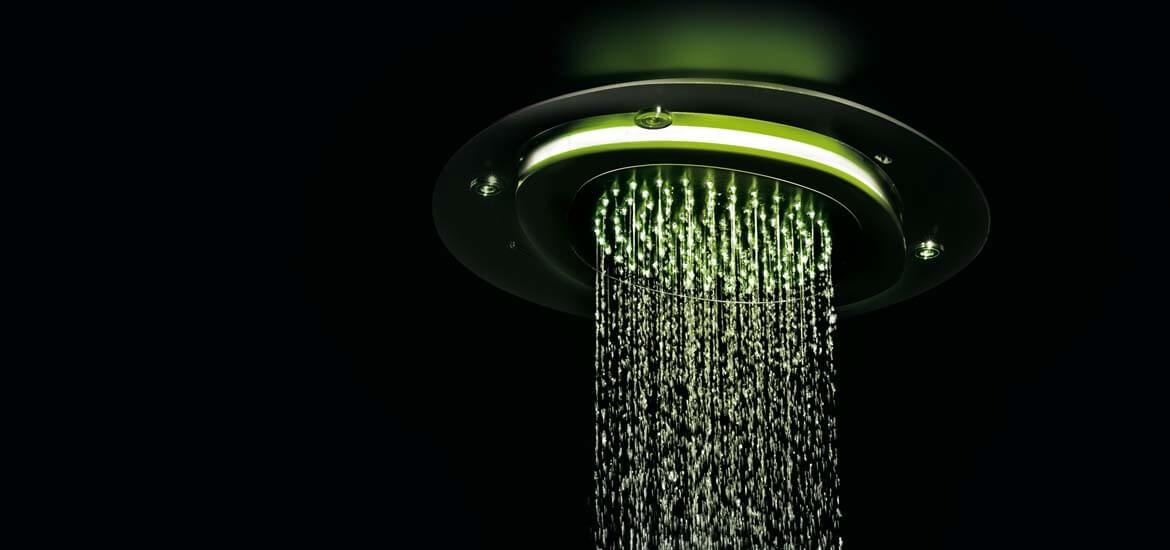 Lakke paigaldatud dušipea rohelise LED-valgustusega, kust langevad ühtlased veejoad tumedal taustal.