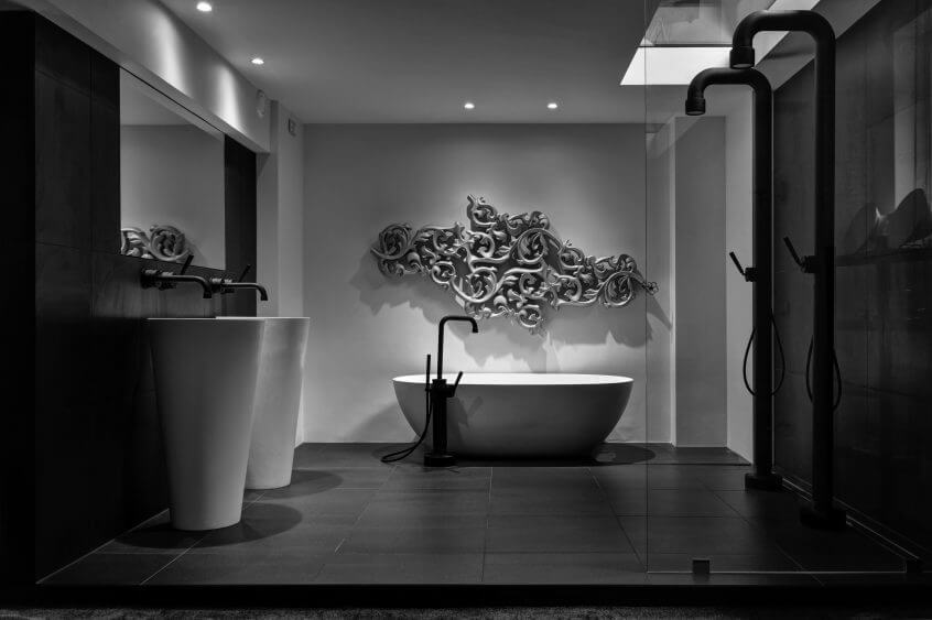 Dramaatiline must-valge vannituba, kus kõrged valamud, ovaalne vann ja matt mustad segistid loovad luksusliku kontrasti ja kunstilise keskpunkti.