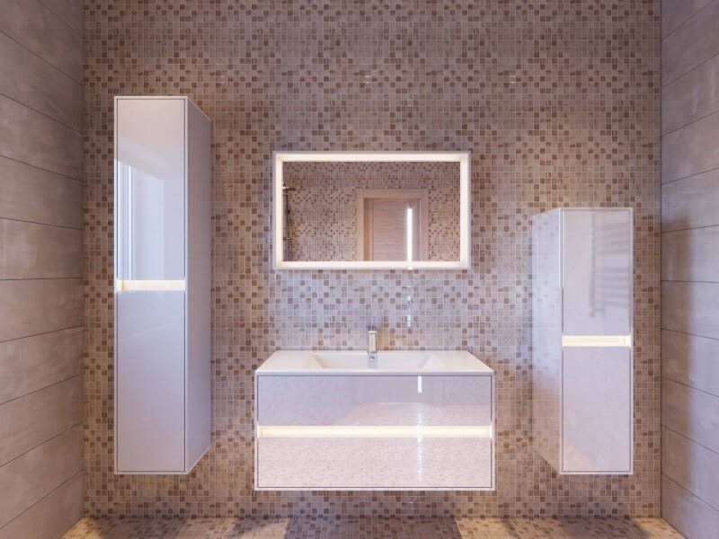 Beežide mosaiikplaatidega vannituba, mille keskmes on l&auml;ikiv valge vannitoam&ouml;&ouml;bel LED-valgustusega. Komplekti kuuluvad k&otilde;rged seinakapid, valamu koos sahtlitega ja valgustatud peegel.