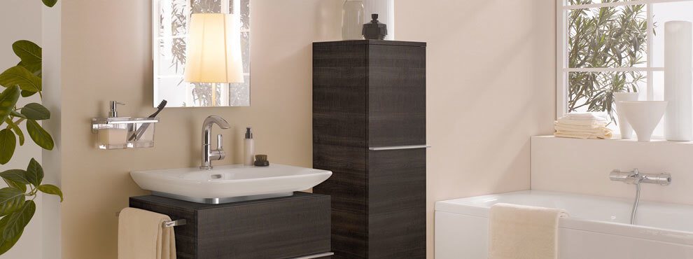 Heledates toonides vannituba tumepruuni valamukapi ja kõrge seinakapiga. Aken, peegelvalgusti ja suur vann paremal küljel.