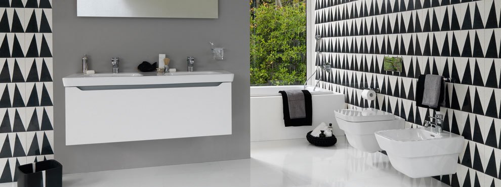 Modernne vannituba valge rippkapi, mustvalge geomeetrilise seinaplaadi ja vanni kõrval asuva WC ning bideega.