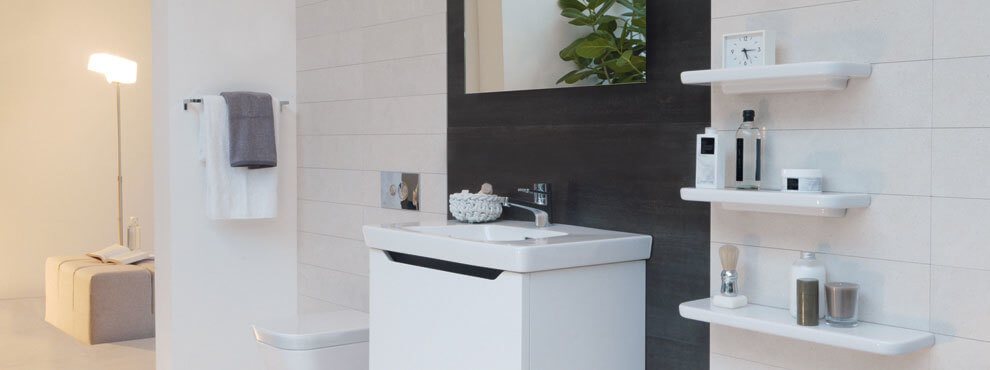 Heledates toonides vannituba musta taustapaneeli, väikese valge valamukapi ja seinale kinnitatud riiulitega.