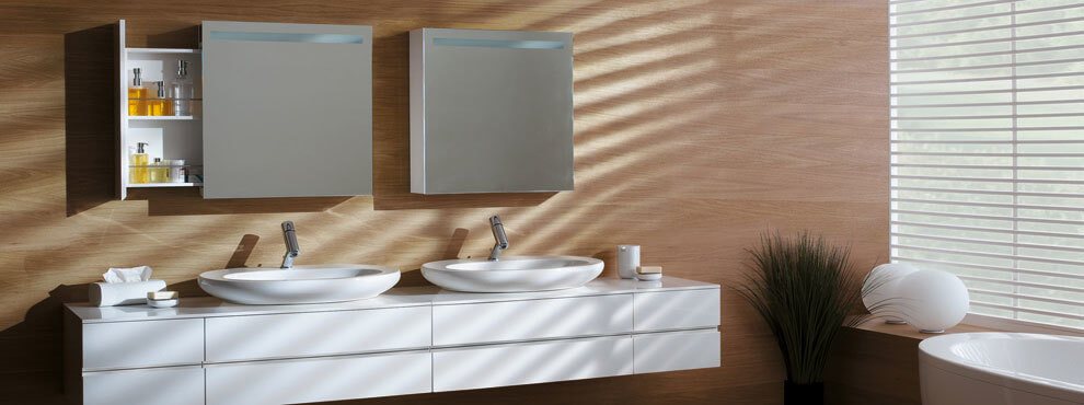 Valge riputatud vannitoakapp kahe ümmarguse valamu ja kahe peegelkapiga, millest üks on avatud ja täidetud kosmeetikaga.