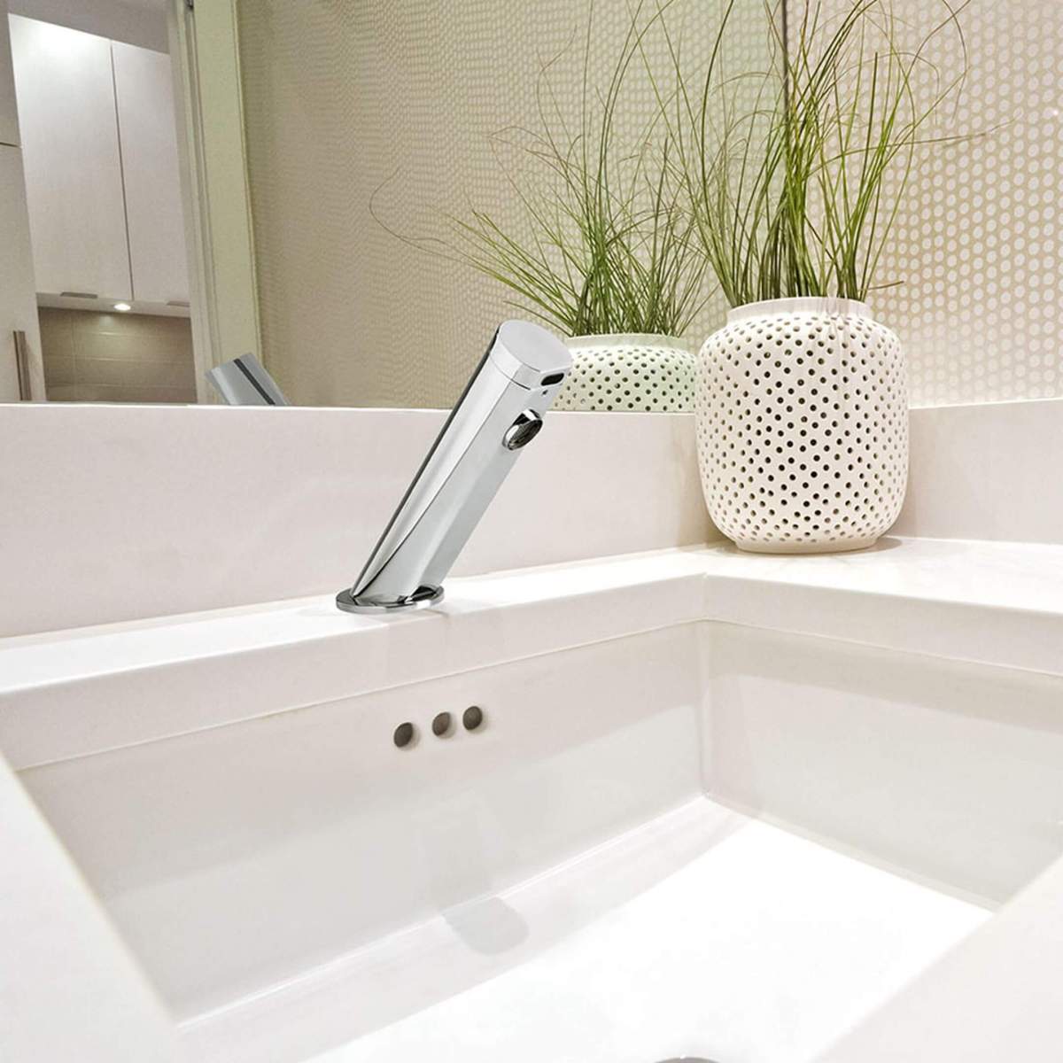 Kaldus sensorsegisti valgel vannitoavalamul, taustal dekoratiivne lillepott k&otilde;rrelistes toonides.