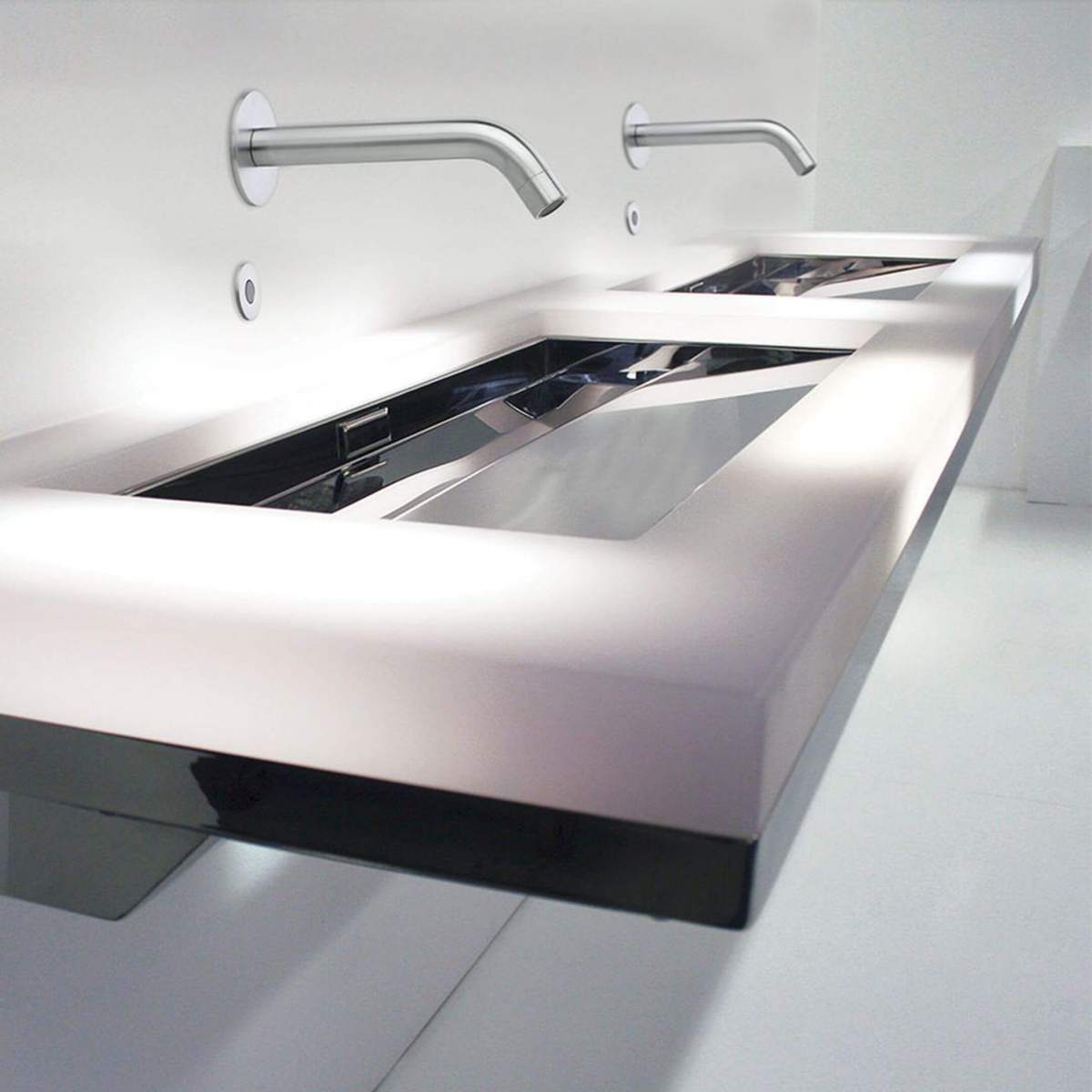 Kaasaegne topeltvalamu seinale kinnitatud tila ja sensornuppudega minimalistlikus valges ruumis.