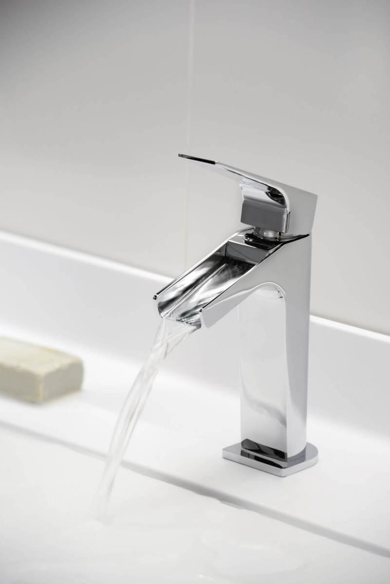 L&auml;ikiv kraan segistiga, millelt voolab vesi valgesse valamusse.