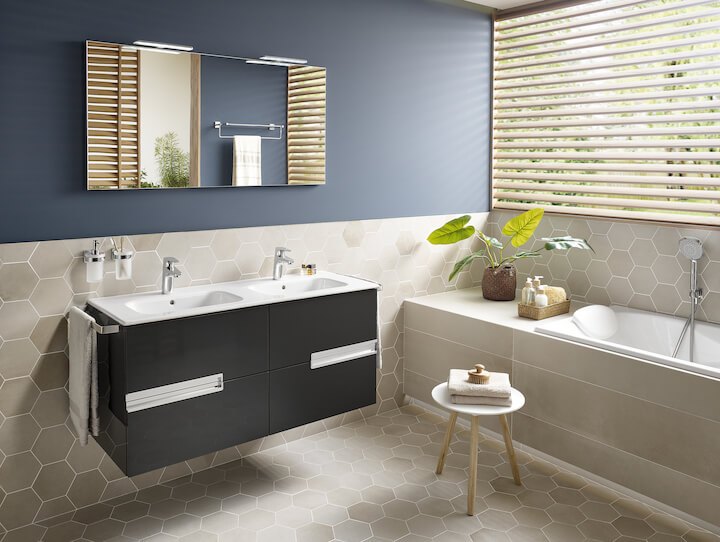 Must kraanikauss kapp, peegel ja kuusnurkne plaatide muster vannitoas, kõrval vann ja taim.