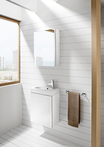 Väike valge kraanikauss koos peegli ja rätikuhoidjaga, aknast avaneva linnavaatega valges vannitoas.