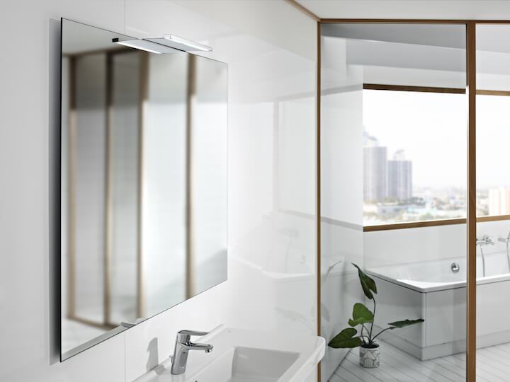 Suur peegel vannitoas, valge kraanikausi ja kraaniga, aknast avaneva linnavaatega.