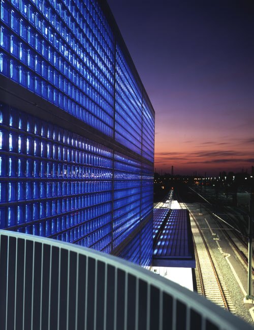 Sinise valgustusega klaasplokkidest fassaad, taustal õhtune taevas.