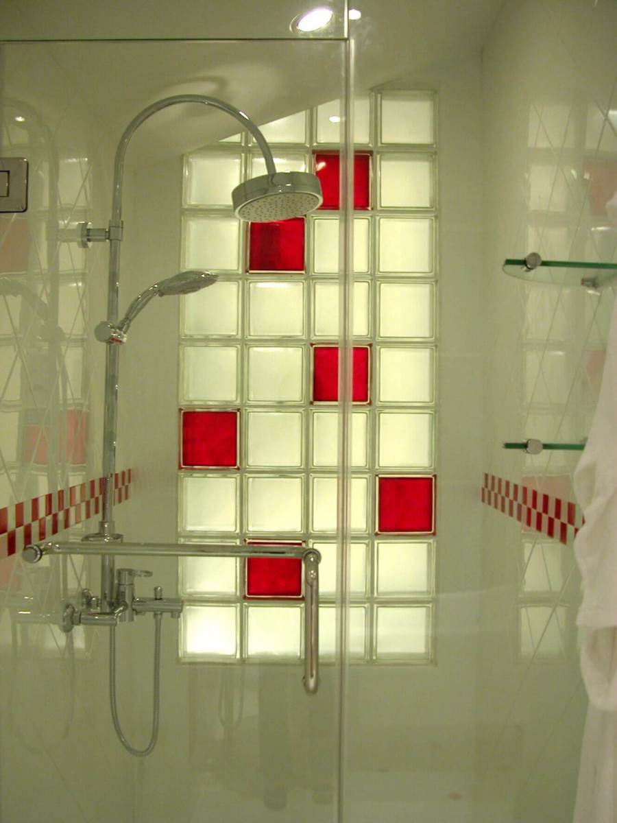 Duširuumi klaasplokkidest sein, millel on punased klaasplokid, ja läbipaistev klaasust koos dušši pea ja segistiga.