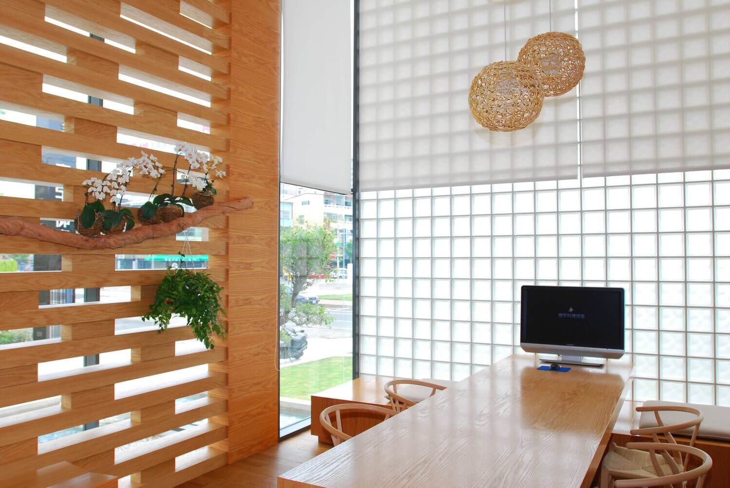 Klaasplokkidest seinaga minimalistlik interjöör, kus on puidust mööbel ja taimed.