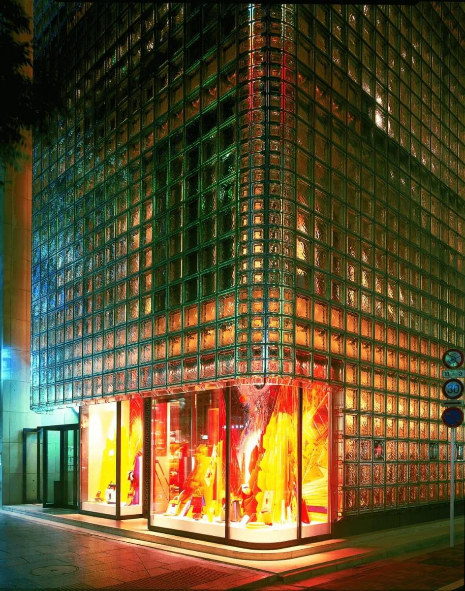 Klaasplokkidest fassaadiga hoone nurk, mille esikus on värvikas vitriin ja valgustus, öösel tehtud pilt.