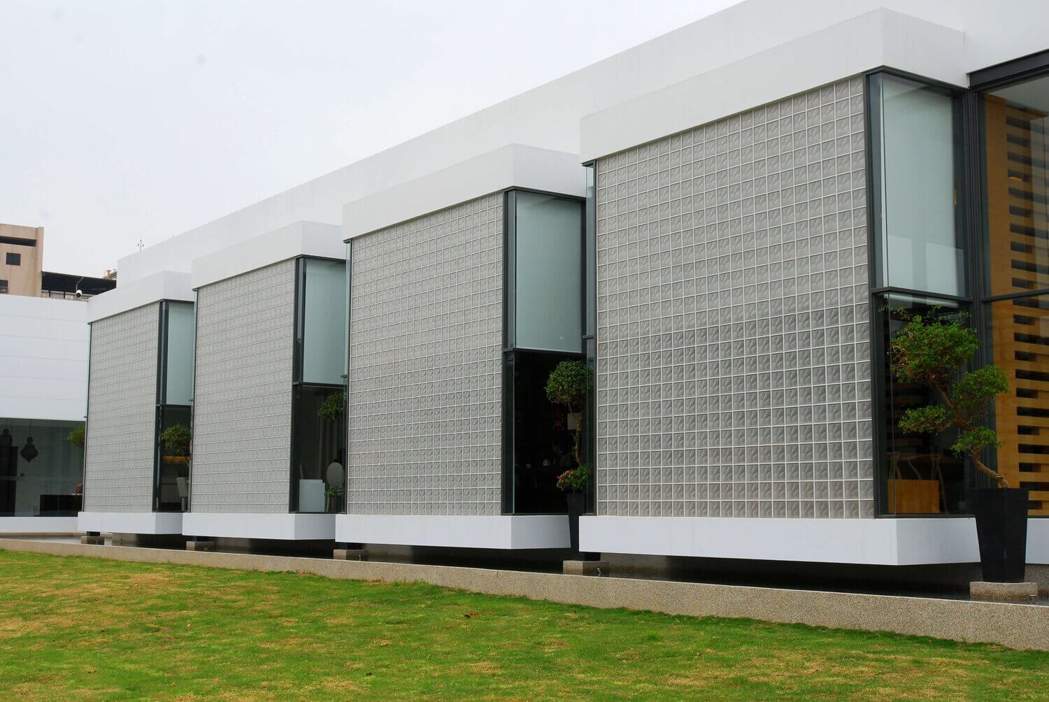 Klaasplokkidest fassaadiga kaasaegne hoone, millel on aknad ja roheline muru.