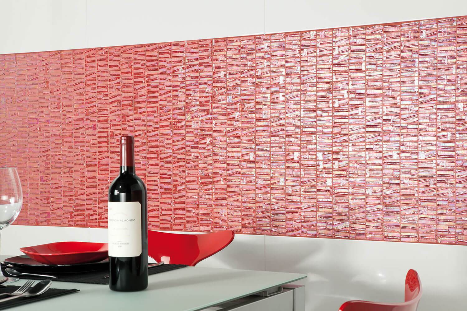 L&auml;ikivast roosakaspunasest lainelisest klaasmosaiigist k&ouml;&ouml;gisein, mille ees on punased toolid ja klaaslaual veinipudel koos n&otilde;udega.